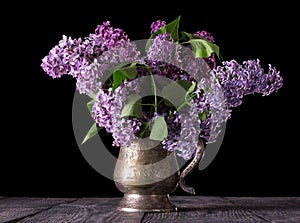 Bouquet of lilac in an old vase isolated on black background