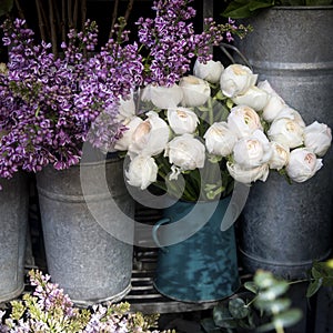 Bouquet of lilac and white ranunculus in tin buckets for sale at the entrance to the store
