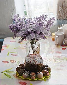 Bouquet of lilacs near Easter cakes and colored eggs.