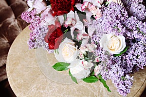 Bouquet of lilacs and red peonies on marble table