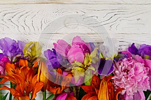 Bouquet of lilies, peonies and iris flowers on white wooden background. Top view, copy space