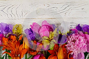 Bouquet of lilies, peonies and iris flowers on white wooden background. Top view, copy space