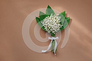 bouquet of lilies of the valley and space for text on beige background