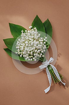 bouquet of lilies of the valley and space for text on beige background