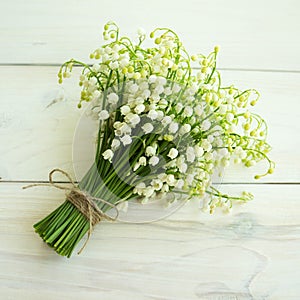 A bouquet of lilies of the valley on a wooden surface.