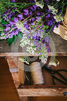 A bouquet of lupines and wild carrots on a vintage table, dark and moody style