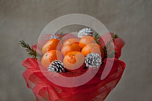 Bouquet of mandarins and Christmas tree branches. New Year`s edible bouquet of fruits. Gift for Christmas. DIY gift