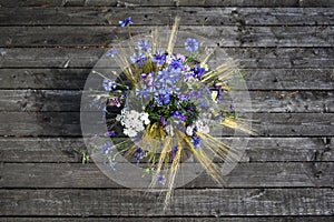 A bouquet of meadow wild flowers, top view, on a dark wooden background