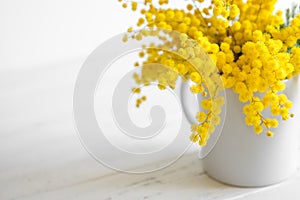 Bouquet of mimosa flowers on white wooden background. Springtime photo