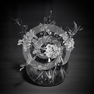 Bouquet of mixed spring flowers and blooming spring flowers in a little glass, round vase. Black and white photography