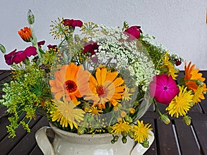 Bouquet of modest summer meadow and garden flowers in the ceramic vase on the wooden table,close up