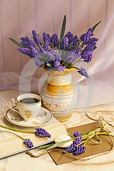 Bouquet of muscari flowers in a vintage vase. Cup of coffee, book and romantic flowersÃÅ½.