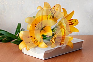 Bouquet of orange lilies on a book, a gift on the occasion of a solemn event