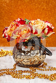 Bouquet of orange and red roses in golden vase