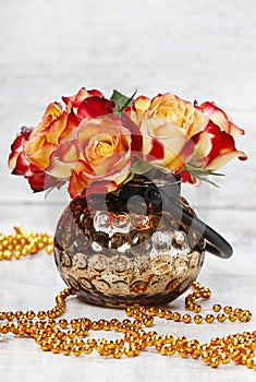 Bouquet of orange and red roses in golden vase