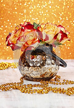 Bouquet of orange and red roses in golden vase