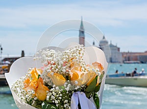 A bouquet of a orange roses at the San Giorgio Maggiore island background in tne lagoon of Venice, Italy