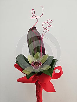 Bouquet with orchid and herbage wrapped in red paper for present isolated on white background