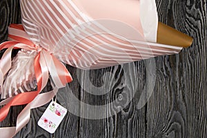 The bouquet is packed in foil and craft paper. Ribbons and tag are visible. Gift for loved ones