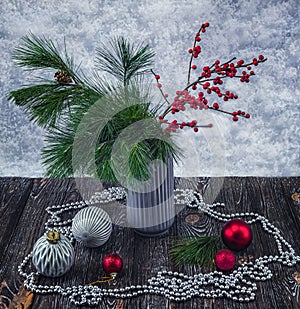 A bouquet of pine and ilex twigs in a vase on a light background. Winter still life.