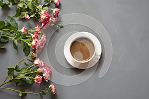 Bouquet of pink bush roses and cup of coffee on shabby chic gray background, top view point.