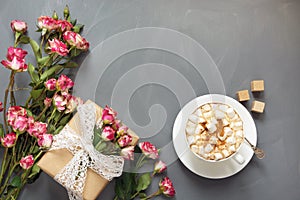 Bouquet of pink bush roses, female gift and cup of coffee on shabby chic background, top view point. Copy space. Mother`s day bac