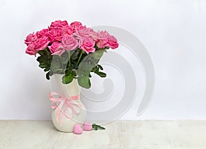 Bouquet pink flowers roses in white porcelain vase and pink hearts on a white table on light background with space for text