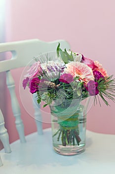 bouquet with pink gerbera and carnations on blue vintage chair.