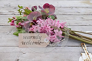 Bouquet with pink hyacinths, Christmas roses and card with text: warmly welcome