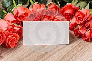 Bouquet of pink red roses and greeting card on a wooden background