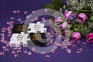 Bouquet of pink roses with baby`s breath next to black and white puzzle pieces
