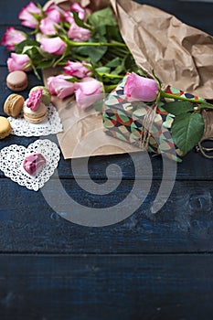 A bouquet of pink roses, a box with a gift. Sweet pasta macaroons of different colors, on Valentine`s Day