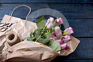 A bouquet of pink roses in brown paper. Color pastry macaroni. Free space for text or postcards