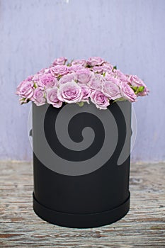 A bouquet of pink roses flowers in a black round box