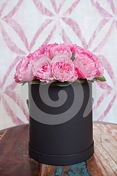 A bouquet of pink roses flowers in a black round box