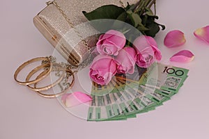 Bouquet of pink roses, golden clutch with cash on a white background
