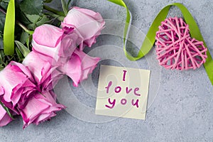 Bouquet of pink roses, a heart and a note with the inscription I love you on the table-the concept of love and care