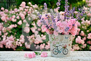 Bouquet of pink roses and lavender on the background of a blooming rose garden