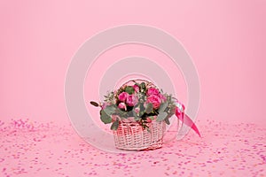 Bouquet of pink roses in a wicker basket on a pink table background. Birthday, Wedding, Mother\'s Day, Valentine\'s Day