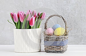 Bouquet of pink tulips and basket of Easter eggs