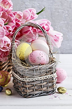 Bouquet of pink tulips and basket of Easter eggs