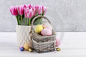 Bouquet of pink tulips and basket of Easter eggs