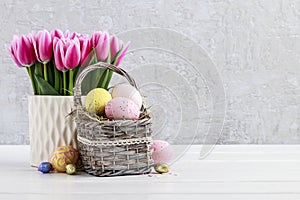 Bouquet of pink tulips and basket of Easter eggs