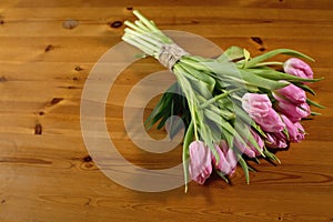 A bouquet of pink tulips on a beautiful wooden background rewound with a craft thread twine