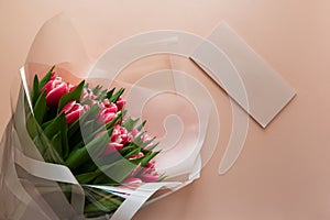 Bouquet of pink tulips with empty card on pink background. Valentines day or Mothers day celebration concept. Top view. Flat lay.