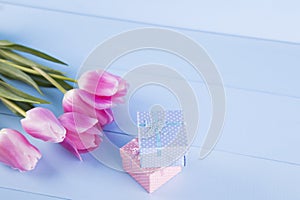 Bouquet of pink tulips with gift box on blue wooden background