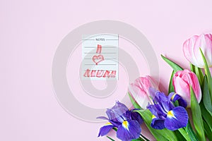Bouquet of pink tulips and irises on pink background. Greeting card for mother\'s day, women\'s day March 8