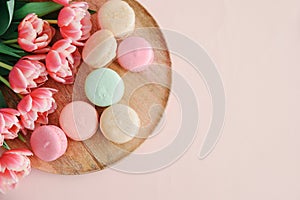 Bouquet of pink tulips and macaroons on pink background. Anniversary celebration concept. Copy space. Top view