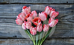 Bouquet of pink tulips in the shape of a heart on a wooden background