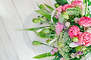 Bouquet of pink white green flowers arranged on wooden background. Roses, sedum, hosta, seed pods and grasses